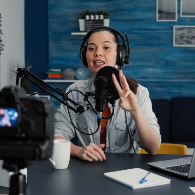 Famous internet podcaster getting ready for streaming while starting to discuss worldwide events with audience. Creative digital content creator sitting at home studio desk while putting on headphones